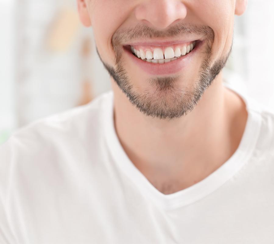 A man smiles after taking wisdom teeth removal services from a dentist