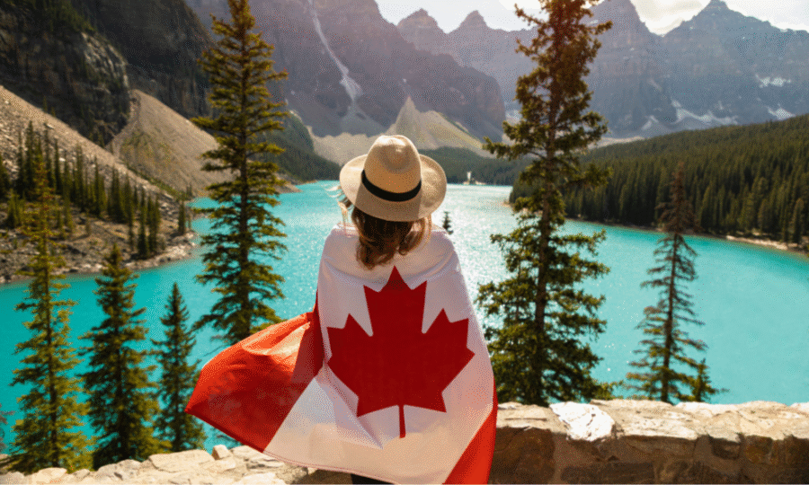 A woman wearing the Canadian flag near a lake